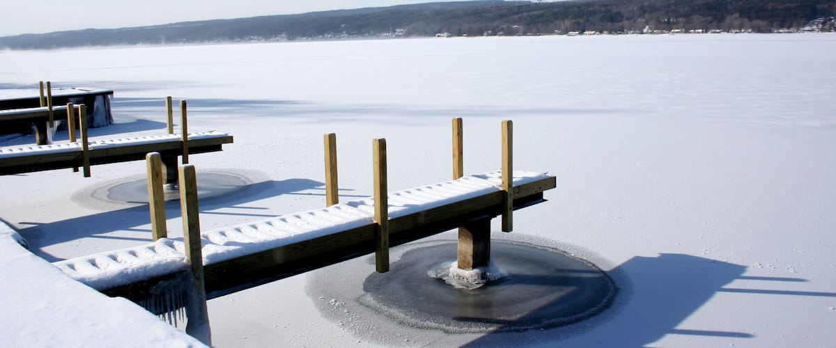 View of snow covered piers on frozen Keuka Lake in the Finger Lakes area of New York. Blue sky, clouds and opposite shore beyond.; Shutterstock ID 71665858
