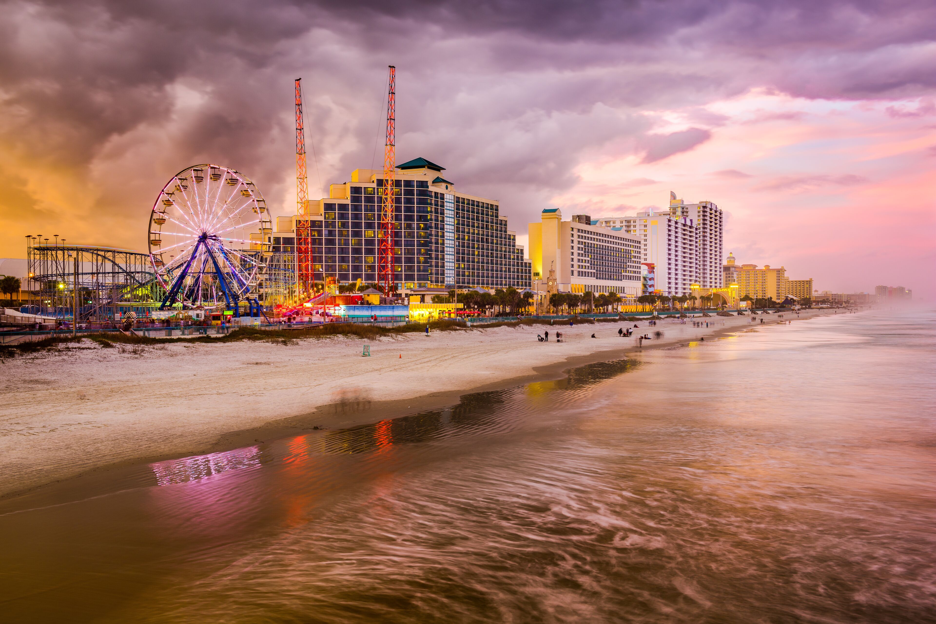 A beach with a Ferris wheel, a hotel, and a crane.