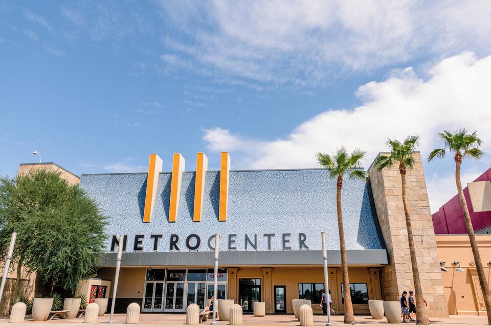 The exterior of the METROCENTER building with palm trees and outdoor seating.