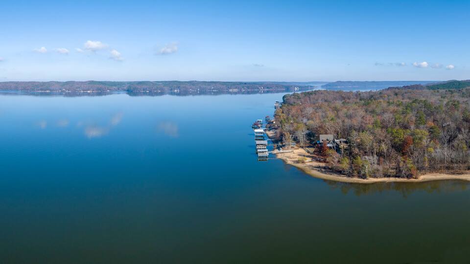 A calm lake with a dock and boats, surrounded by forested hills.