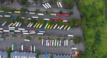 An aerial view of a parking lot with numerous buses and solar panels.