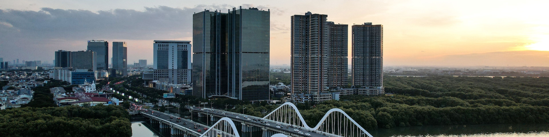 Paisagem urbana com edifícios modernos altos, um rio e uma ponte branca com um design de arco único.