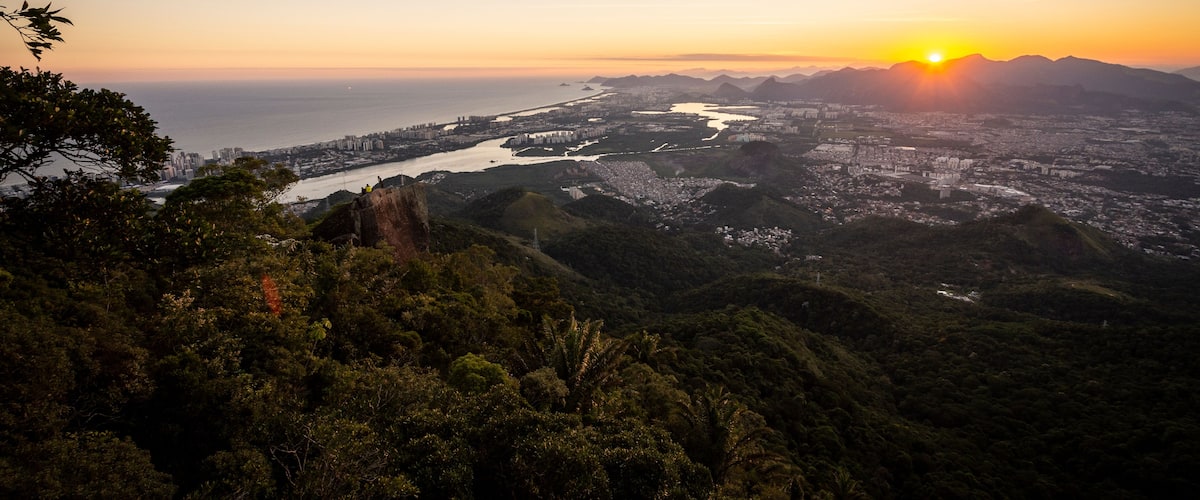 Un paisaje urbano costero al atardecer con montañas en el fondo.