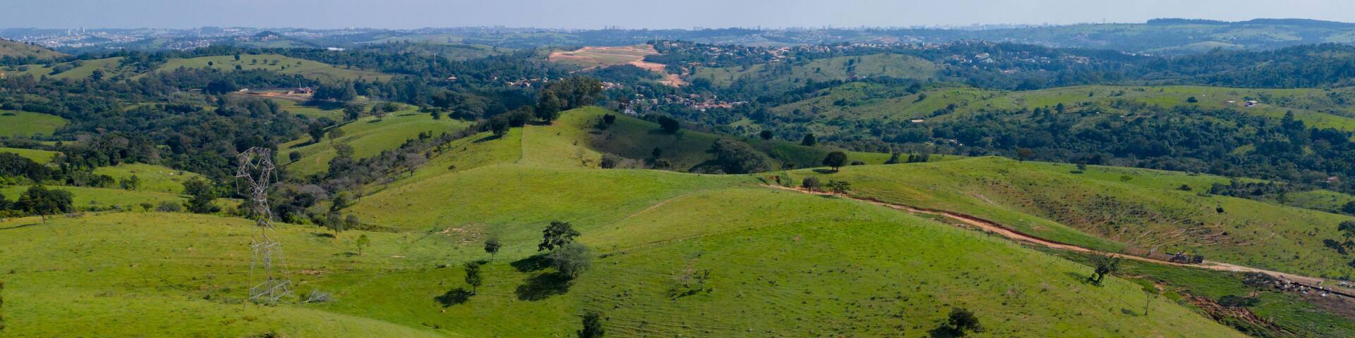 Rolling green hills, a winding road, and distant buildings.
