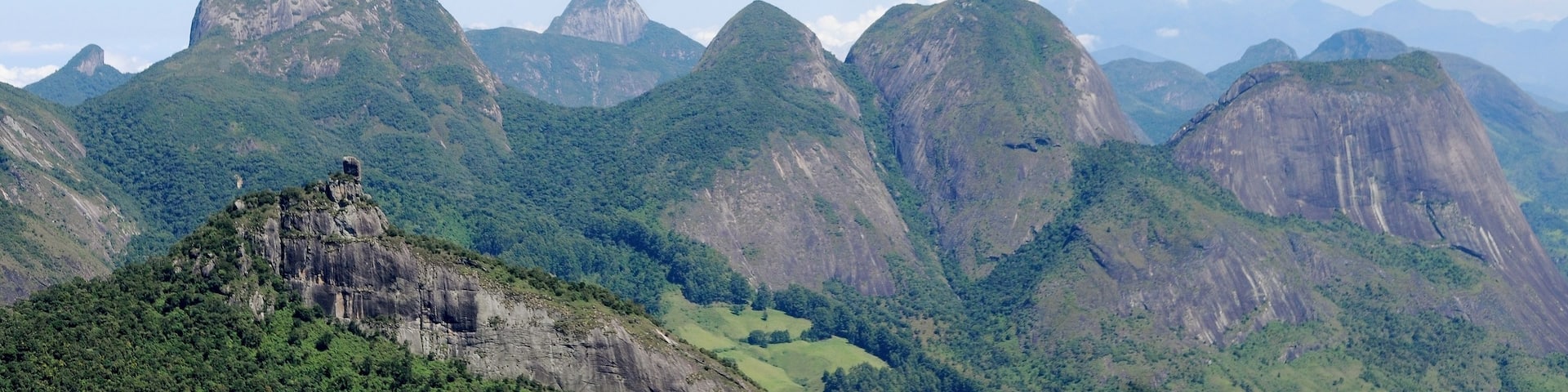 A mountainous landscape with prominent peaks and a rocky outcrop in the foreground.