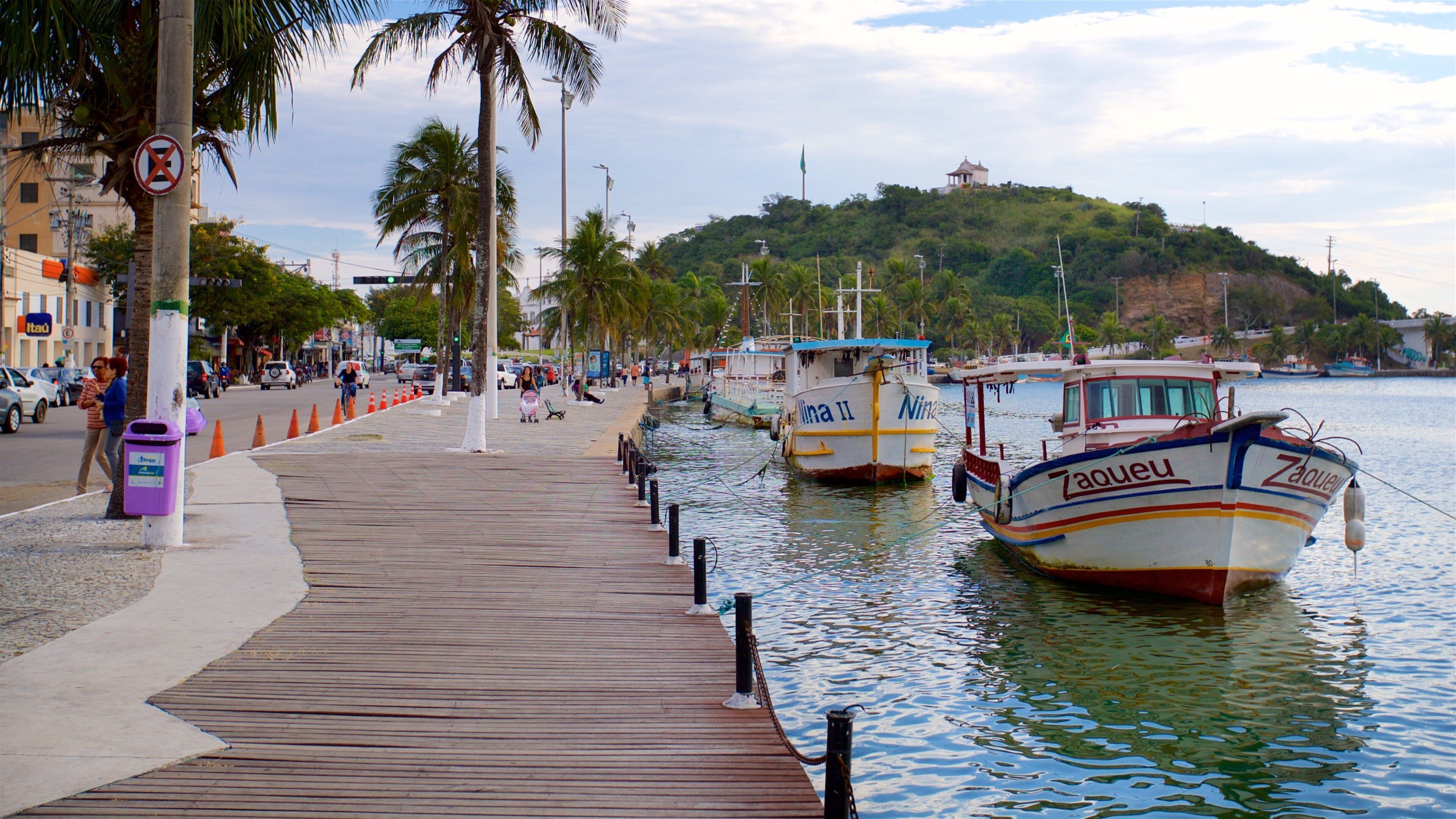 A wooden boardwalk by the water with boats docked.