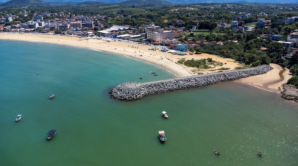 Eine Küstenstadt mit Strand, Booten und einem steinernen Wellenbrecher.