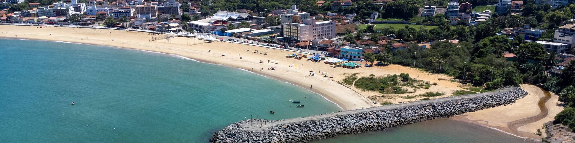 A coastal town with a beach, boats, and a rocky breakwater.