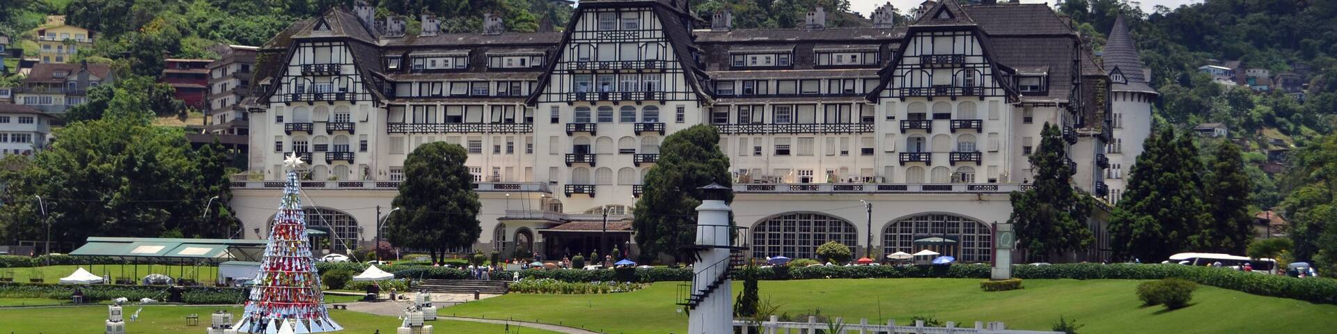 A large castle with a lake in front, surrounded by greenery and hills.