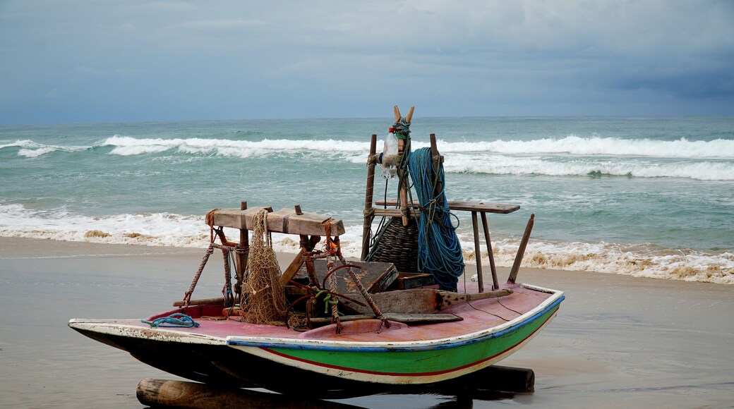 A small boat with a colorful hull on a sandy beach, with the ocean in the background.