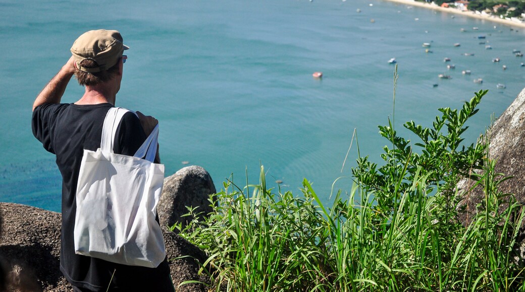 Tourist enjoying the panoramic view of Canto Grande Beach from Morro do Macaco viewpoint in Bombinhas, Santa Catarina, Brazil