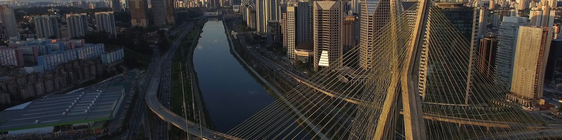 Paisagem urbana com uma ponte pênsil imponente, um rio e edifícios altos.