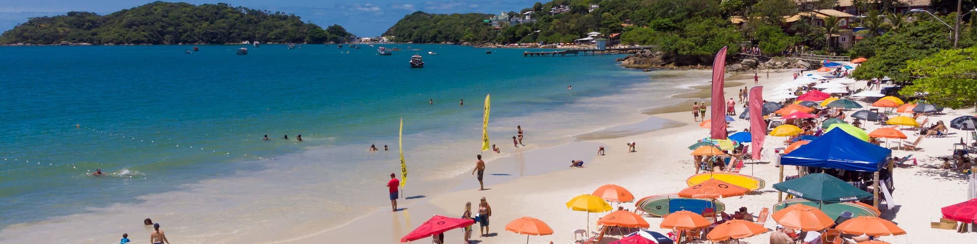 Praia cheia em dia ensolarado de verão cheio de guarda sol coloridos