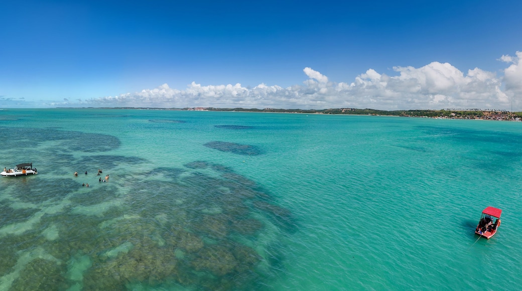 A turquoise sea with clear waters, a small boat, and a red boat on the right.