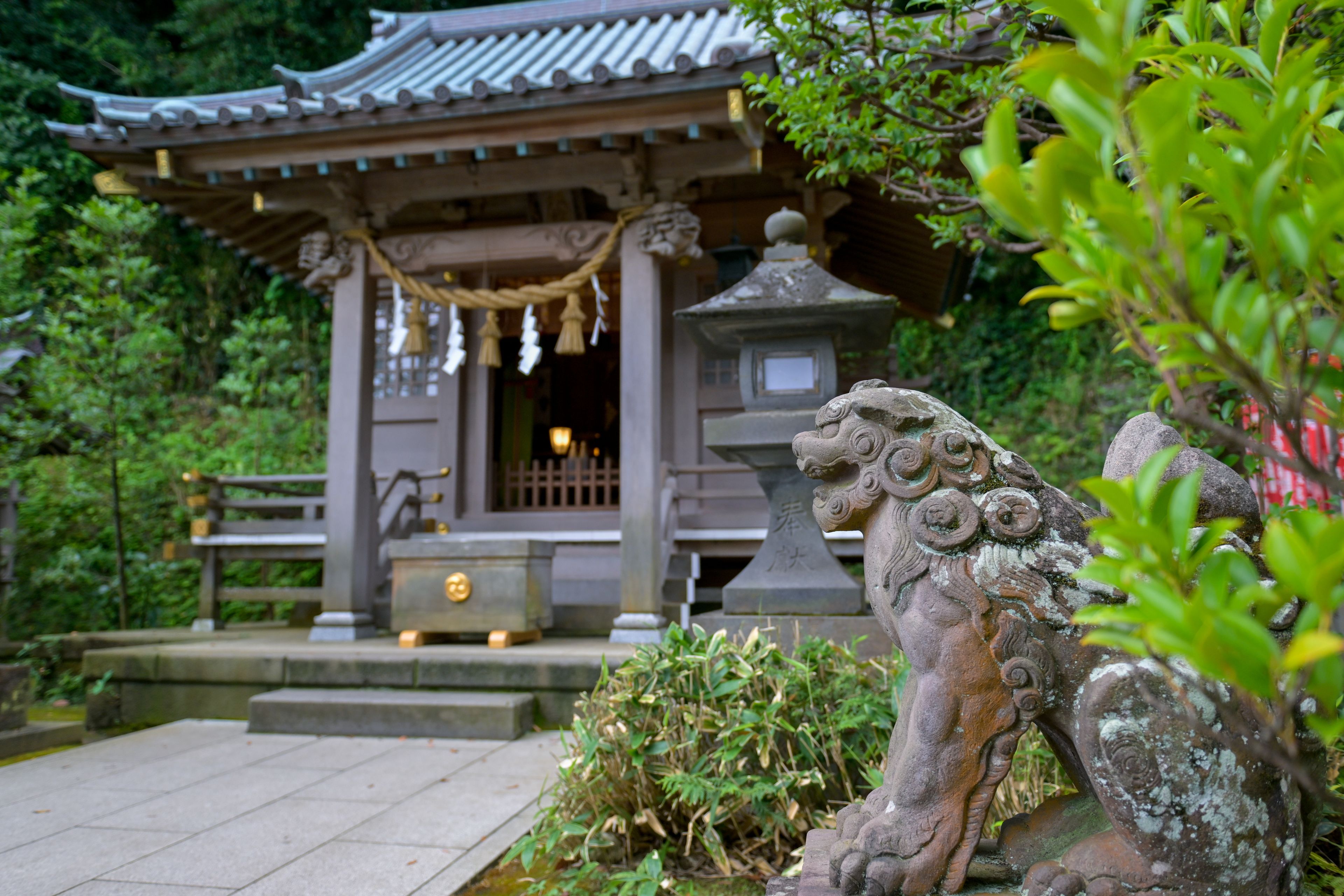 A traditional Japanese temple with a stone lion statue in the foreground.