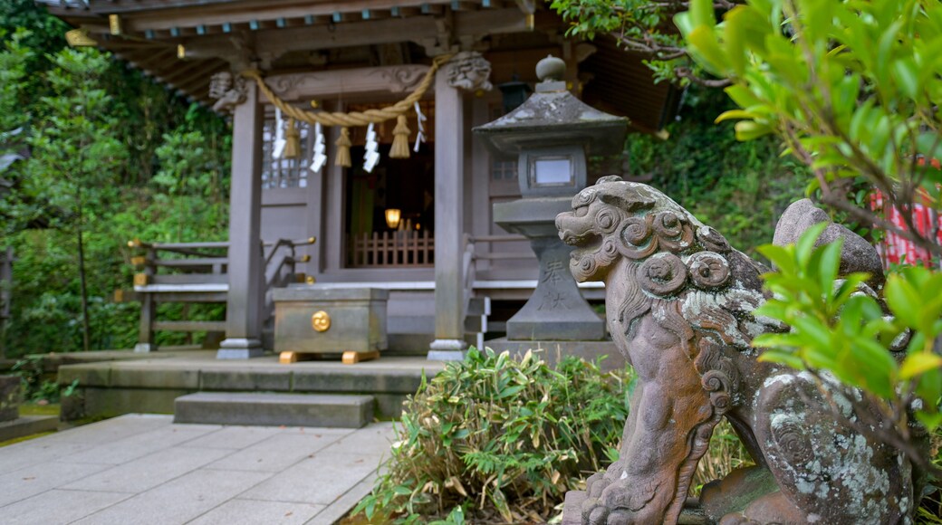 A traditional Japanese temple with a stone lion statue in the foreground.