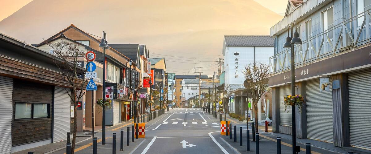A street with buildings, a mountain in the background, and a clear sky.
