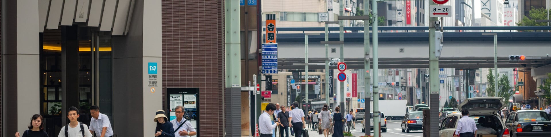 Rua urbana movimentada com pedestres, ciclistas e veículos.