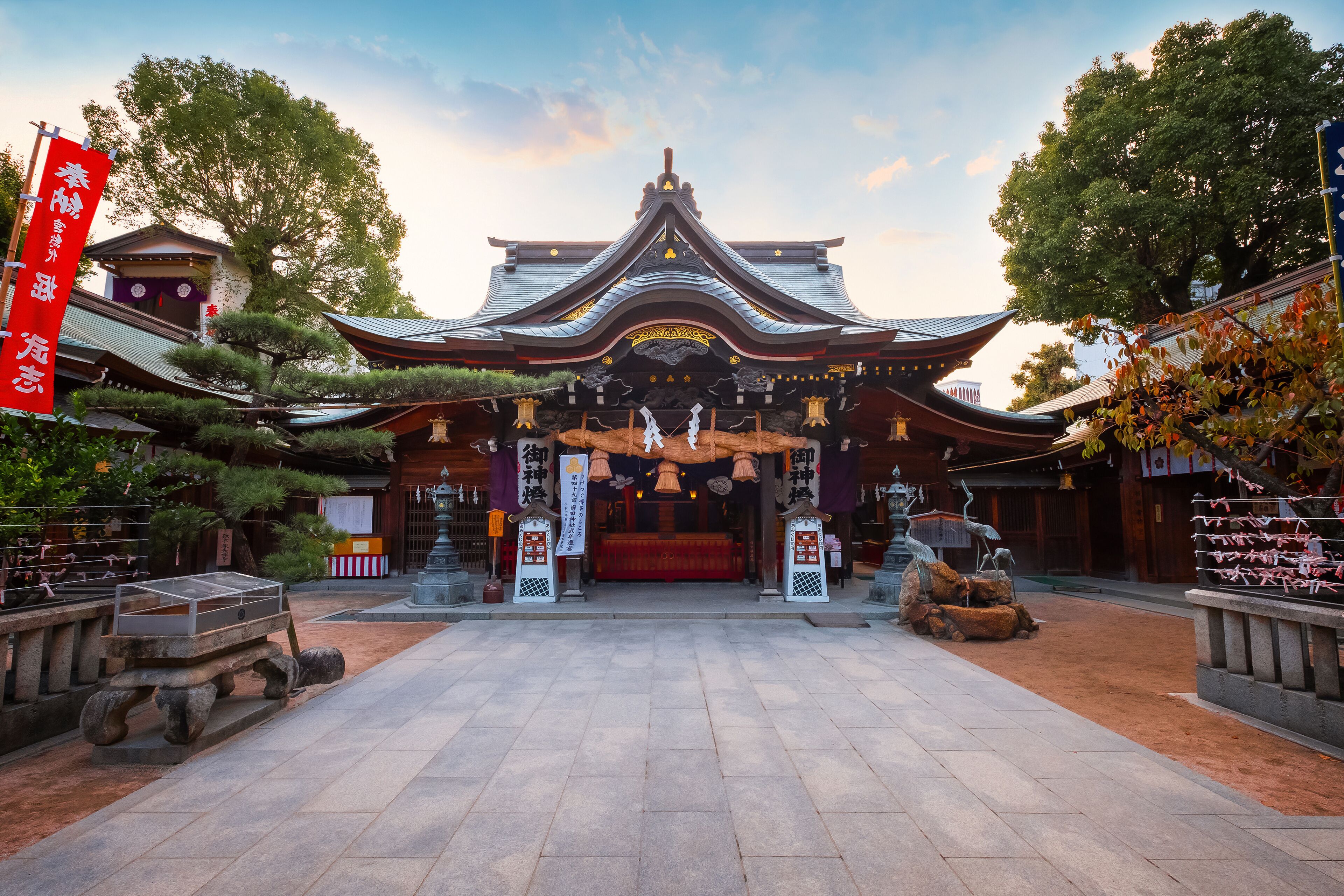 A traditional Japanese temple with a curved roof, stone lanterns, and a red altar.