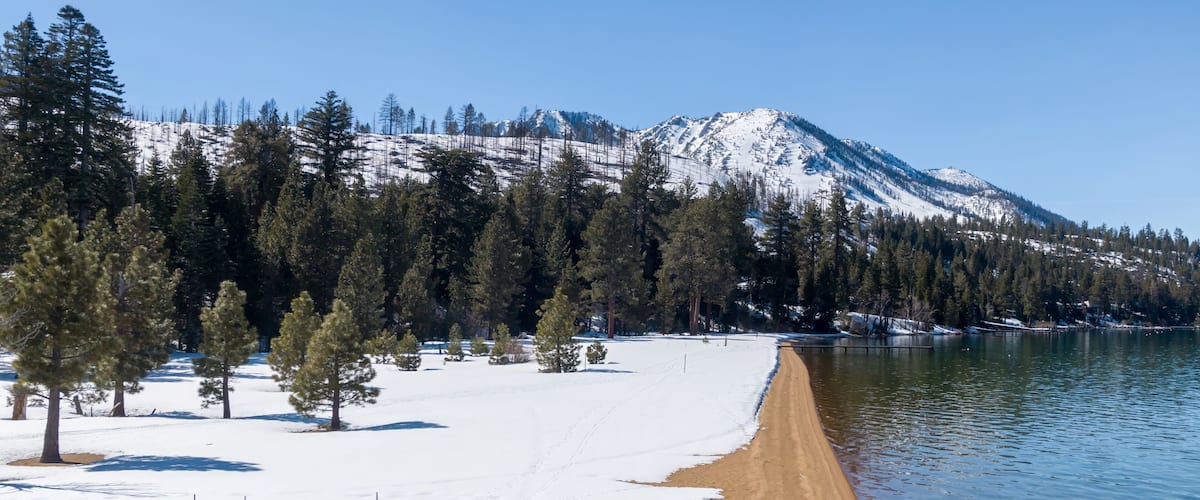 A snow-covered beach with a mountain in the background.