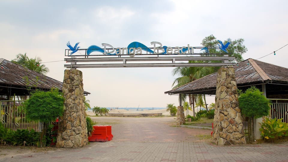 A stone archway with a sign reading "Dona Beach" and a view of the beach in the background.