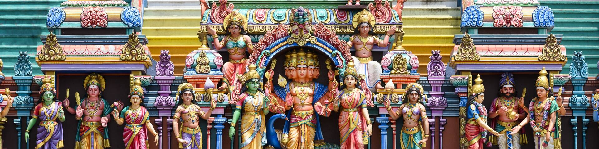 A colorful temple facade with intricate carvings and statues of deities.