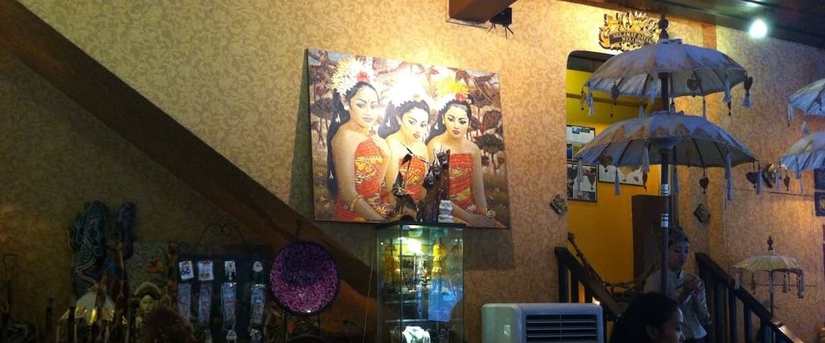 A dimly lit bar with a large painting, decorative umbrellas, and various items on shelves.