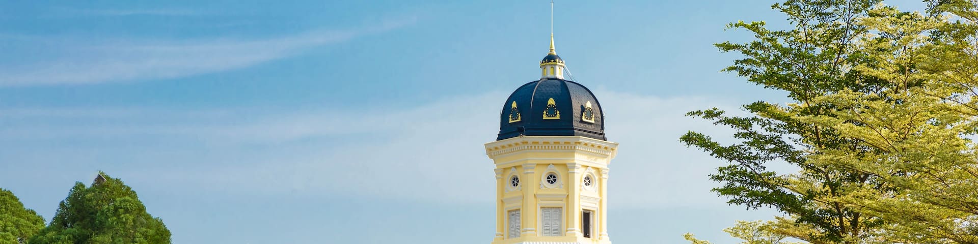 A large yellow building with a blue dome and a tower.