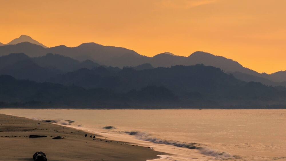 A beach with a mountain range in the background.