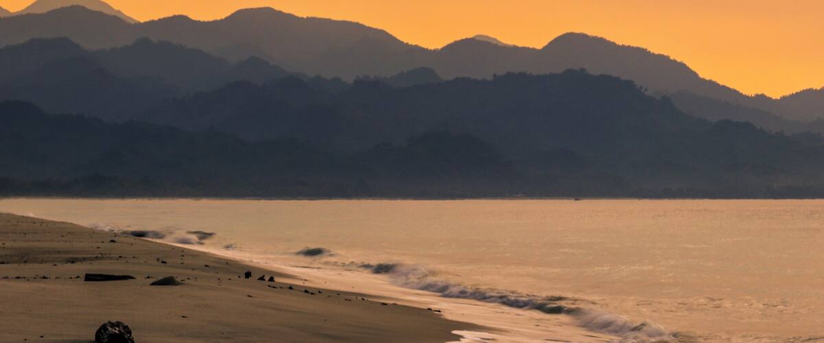 A beach with a mountain range in the background.