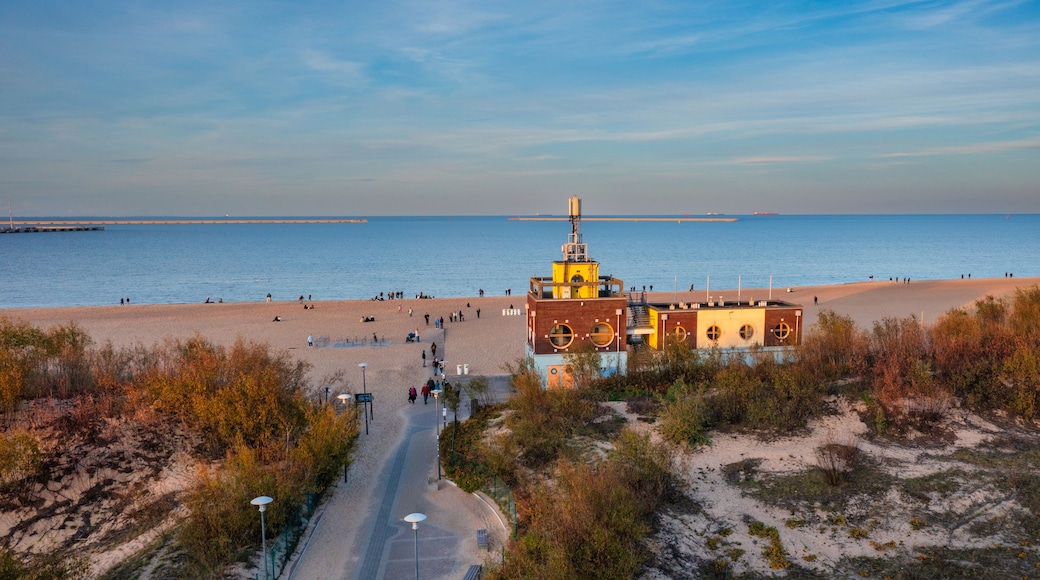 A coastal beach with a lighthouse, sandy shore, and a clear sky.