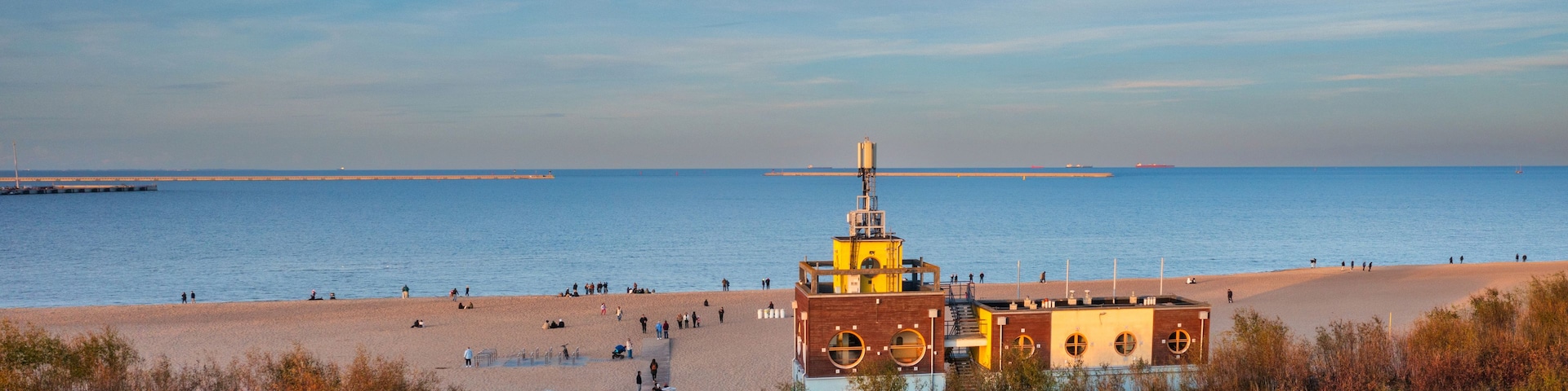 Una playa costera con un faro, orilla arenosa y cielo despejado.