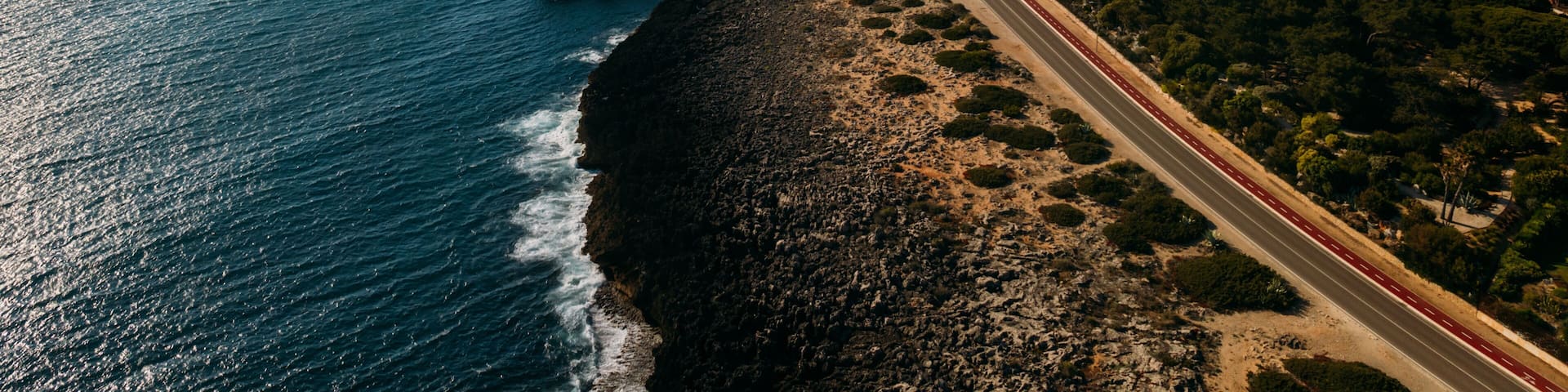Aerial view top down view of of a straight road and rugged coastline at Guincho beach, Cascais, Portugal