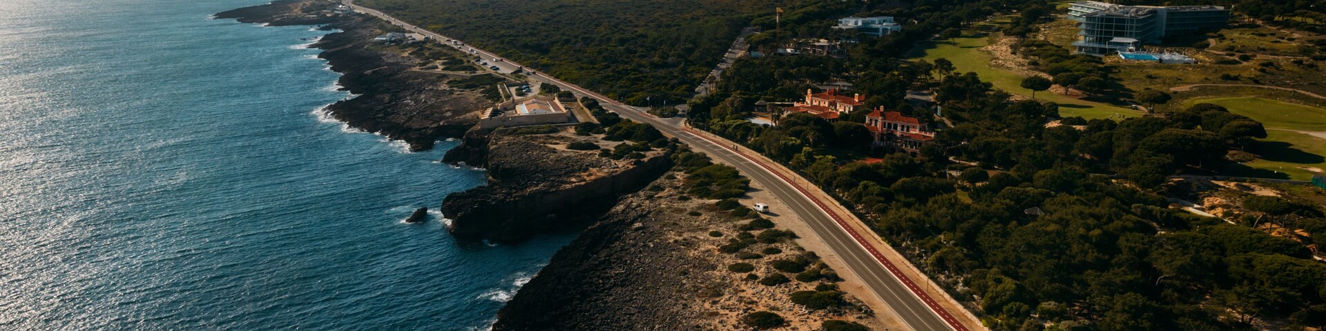 Aerial view top down view of of a straight road and rugged coastline at Guincho beach, Cascais, Portugal