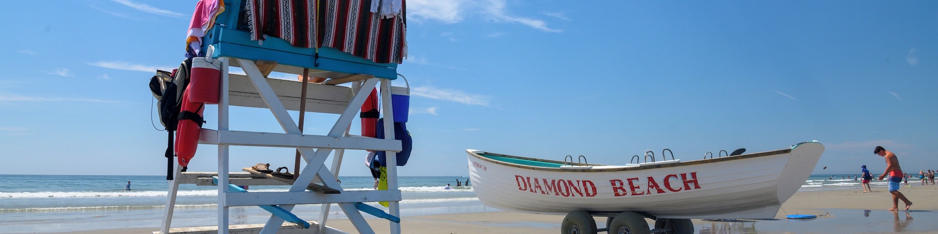 A lifeguard stand with an umbrella, a beach chair, and a boat labeled "DIAMOND BEACH" on the sand.
