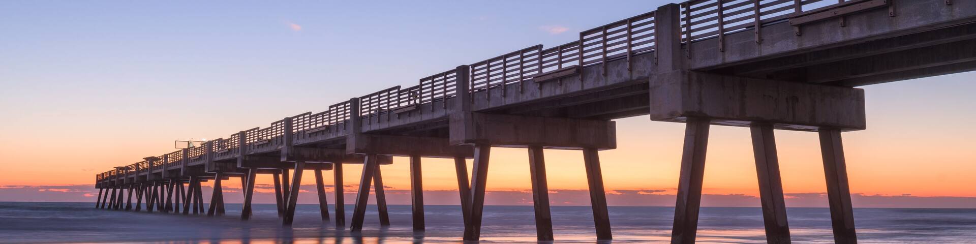 A pier extending into the water with a sunset in the background.
