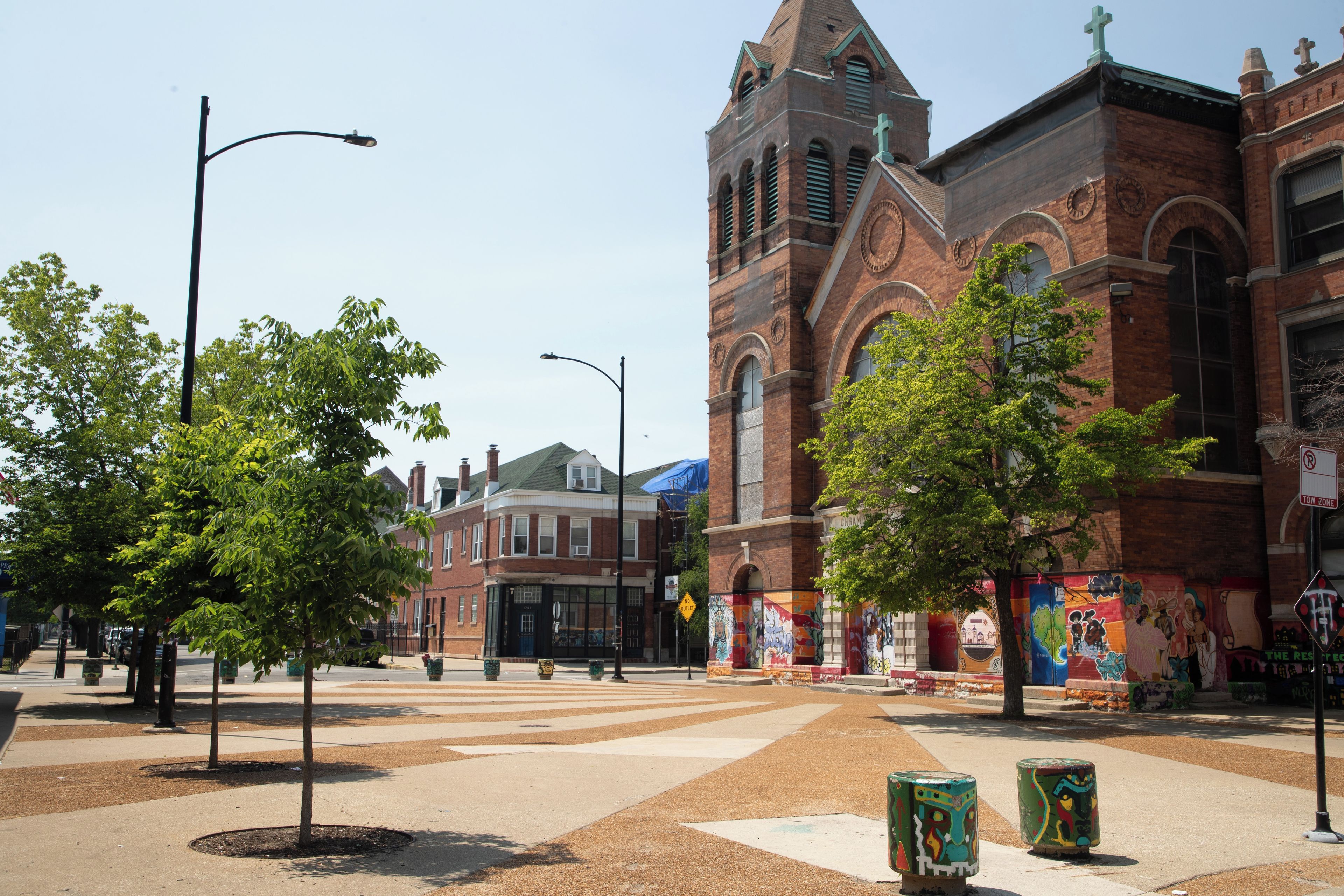 A street with trees, a church, and a building with colorful murals.