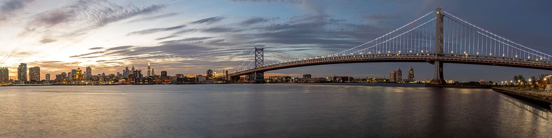 Panorama of the Benjamin Franklin Bridge and the skyline of Philadelphia with the Delaware River at twilight