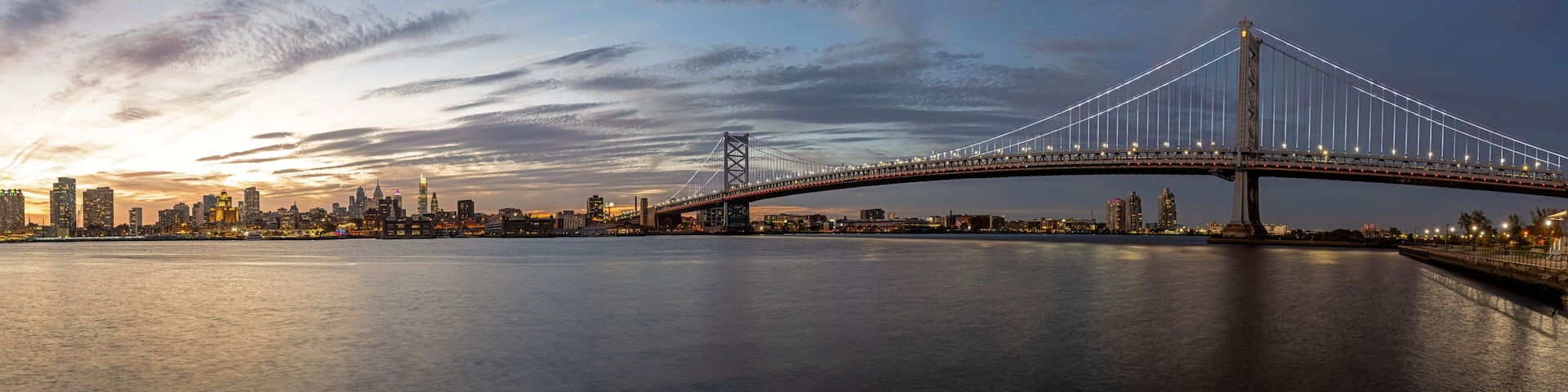 Panorama of the Benjamin Franklin Bridge and the skyline of Philadelphia with the Delaware River at twilight