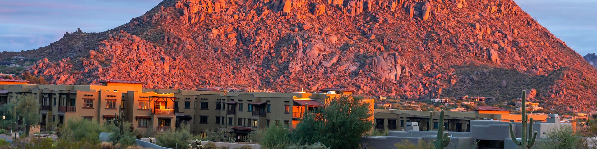 A winding road curving through a desert landscape with a prominent mountain in the background.