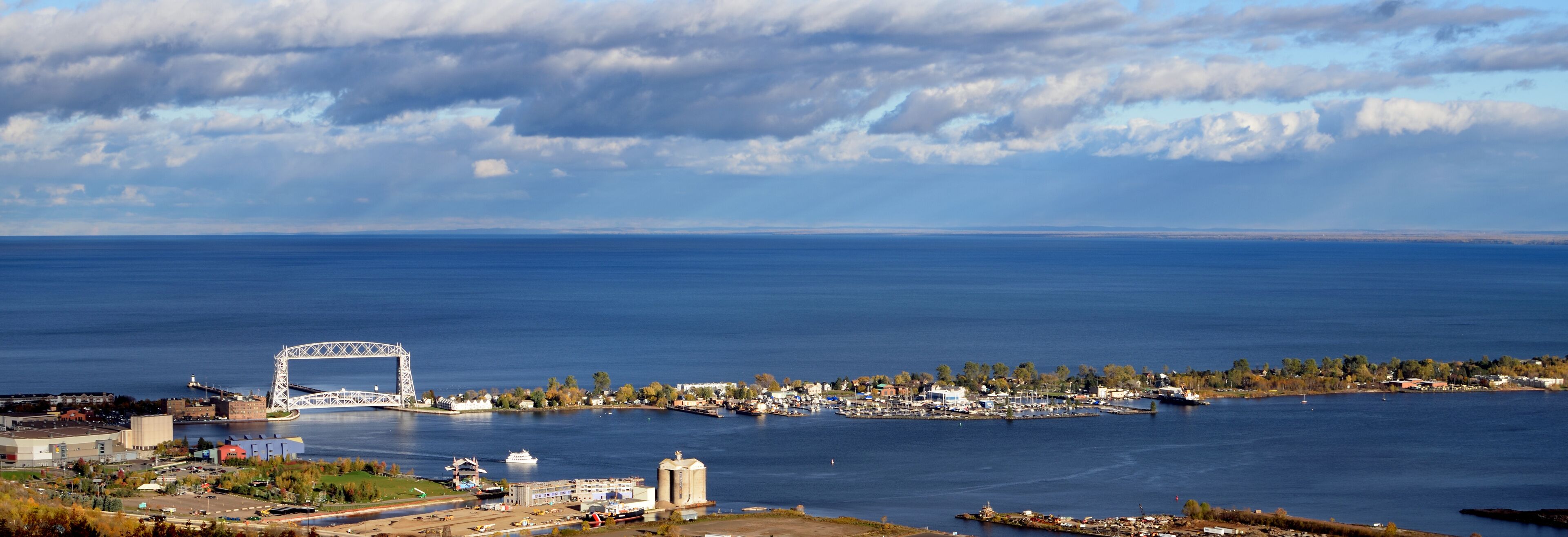 A coastal city with a prominent bridge, marina, and industrial buildings.