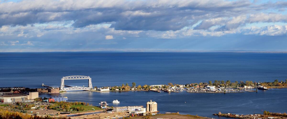 A coastal city with a prominent bridge, marina, and industrial buildings.