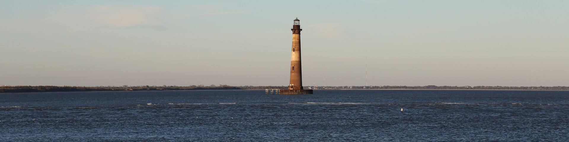 A lighthouse on a pier extending into a calm body of water.