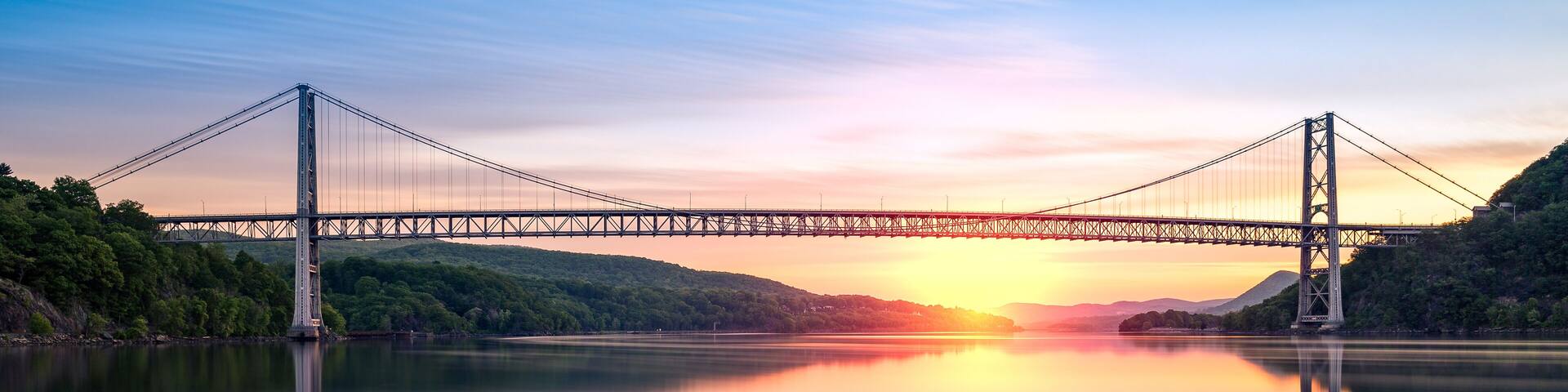 Bear Mountain Bridge at sunrise (long exposure). Bear Mountain Bridge is a toll suspension bridge in New York State, carrying U.S. Highways 202 and 6 across the Hudson River