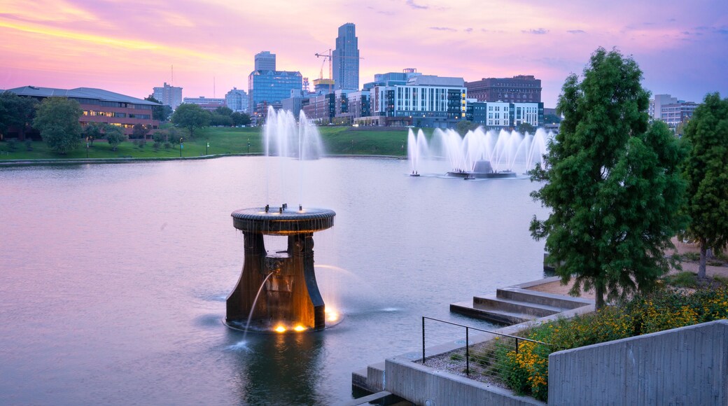 View of Omaha Nebraska skyline at sunset seen from Heartland of America Riverside Park with lake in view.