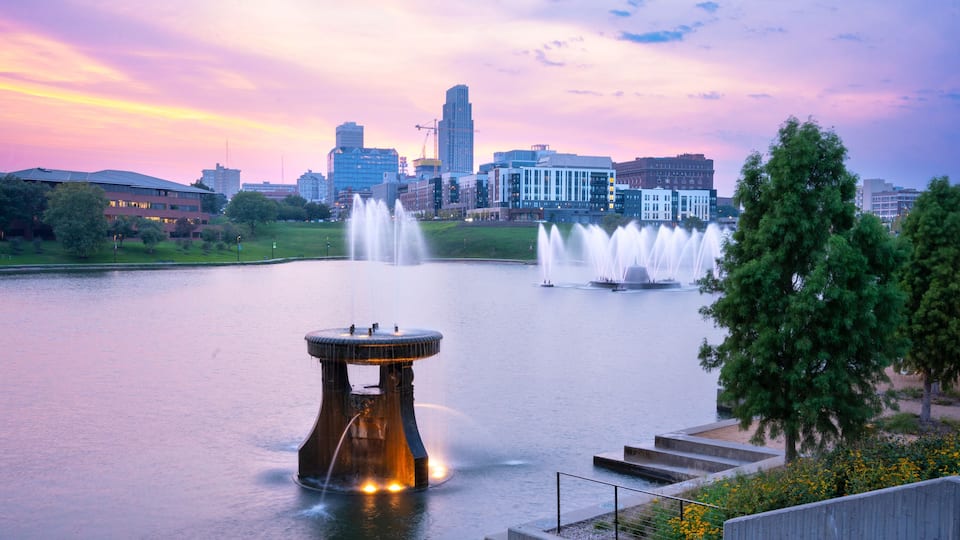 View of Omaha Nebraska skyline at sunset seen from Heartland of America Riverside Park with lake in view.