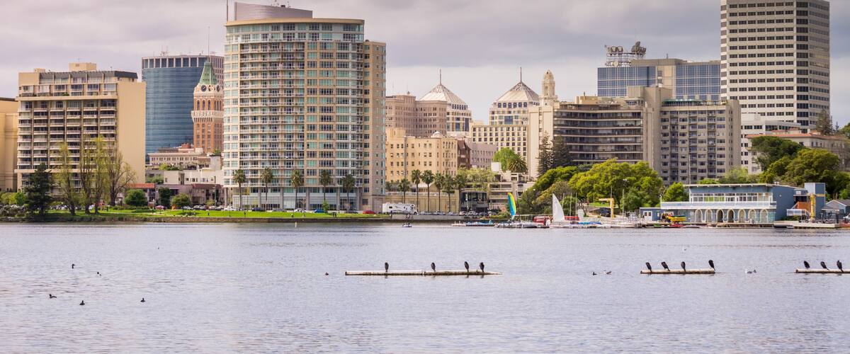 A city skyline with modern buildings and a body of water in the foreground.