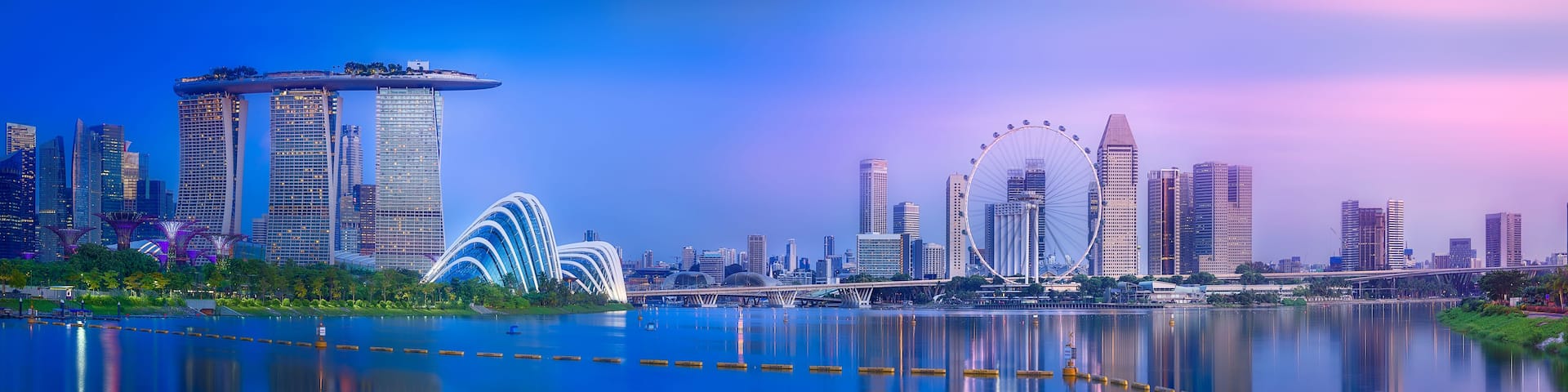A city skyline with modern architecture, including a distinctive bridge and a large Ferris wheel.