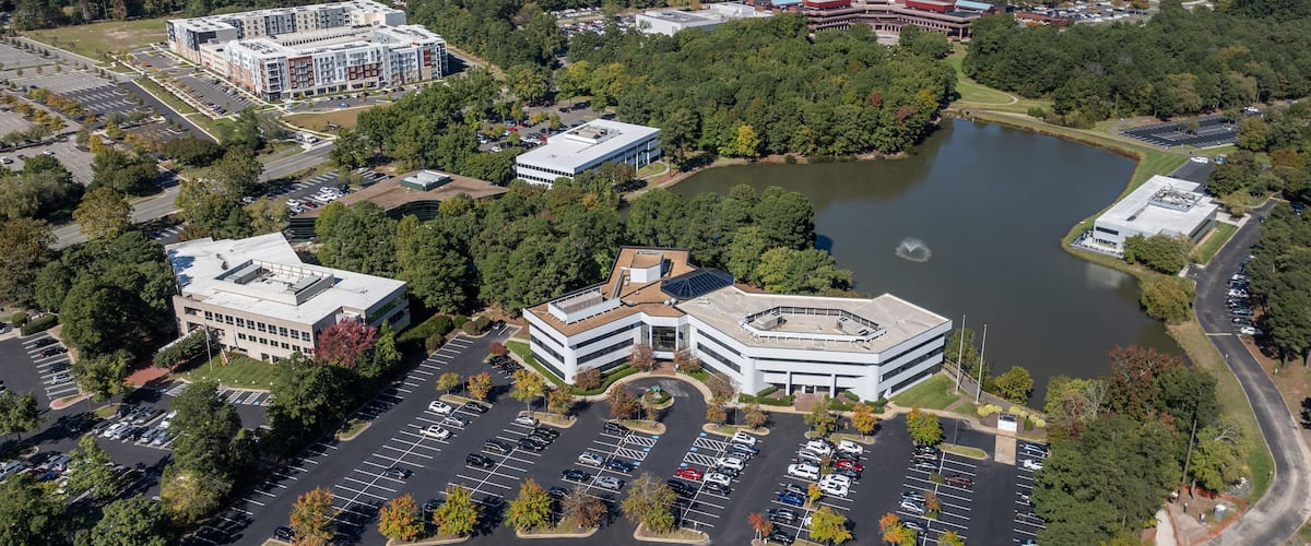 An aerial view of a campus with a large lake, parking lots, and various buildings.