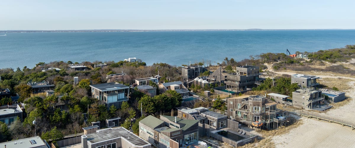 A coastal residential area with modern houses and a beach in the background.